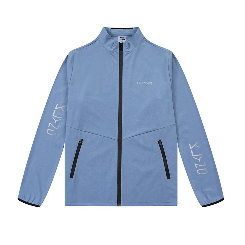 Introducing the AeroFlex Performance Jacket by Klyng: This light blue zip-up features black zippers and a high collar with odor resistance. It displays white text logos on the left sleeve and chest, along with two front pockets for added convenience.