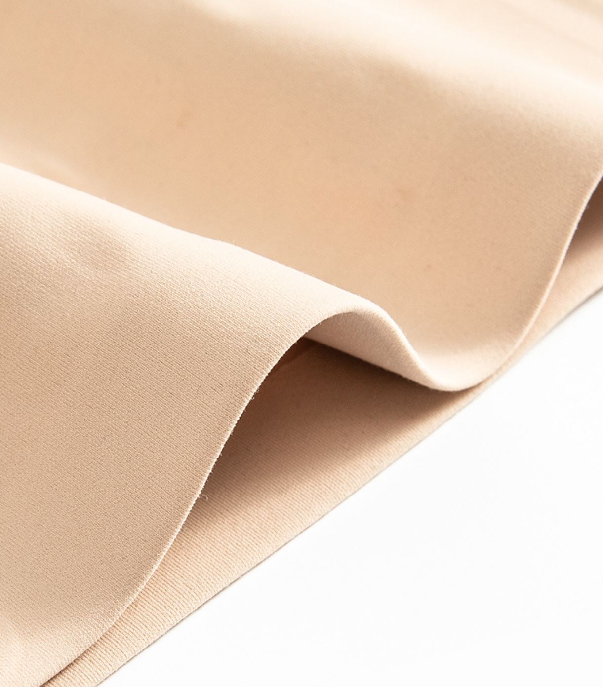 A close-up of the Women PowerCore Super High-Waist Compression Short from Klyng reveals its smooth, beige fabric with gentle folds, highlighting its soft texture and seamless appearance—an innovation reminiscent of performance-enhancing activewear.