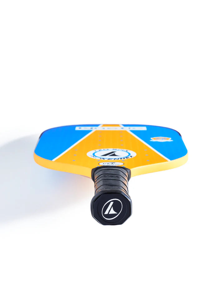 Close-up view of the Prokennex Pro Spin Pickleball Paddle showcasing its vibrant blue and yellow design. The handle, with its black grip and logo, features the advanced Kinetic system engineered for maximum spin. The paddle is positioned vertically to emphasize the handle end.