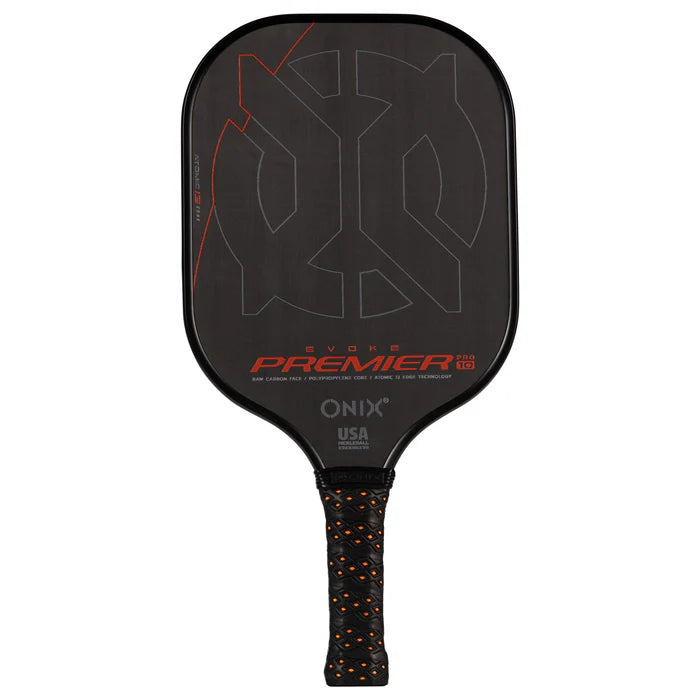 The Evoke Premier Pro Raw Carbon Pickleball Paddle, by Onix, is a lightweight paddle with black as its base color and orange accents. It features a high-performance carbon fiber surface. The grip showcases an eye-catching orange and black pattern, along with text highlighting "USA" and "DFT Technology" to enhance performance.