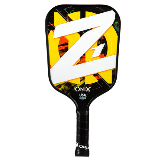 Introducing the Composite Z1 v2 Pickleball Paddle by Onix, showcasing a striking yellow and white Z design against a dark background. The brand name and USA are elegantly displayed in white at the bottom of this tournament play approved paddle. It features composite fiber construction and includes a black handle with a wrapped grip for optimum performance.